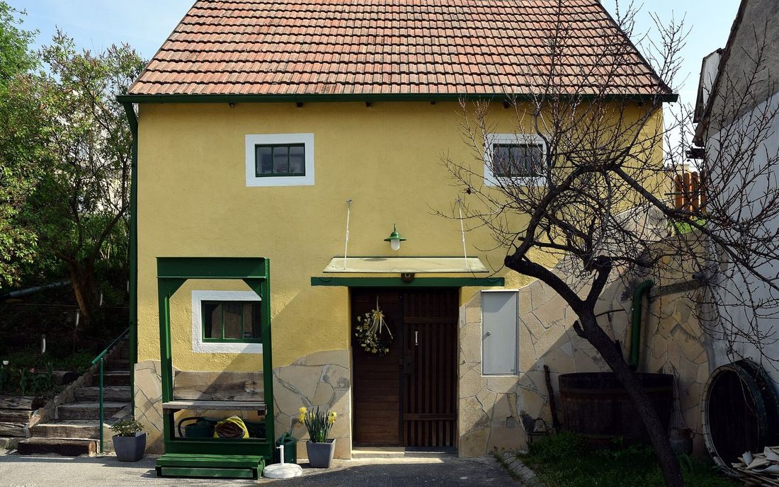 Casa amarela com um pequeno toldo fixo de estrutura metálica verde sobre a porta de entrada