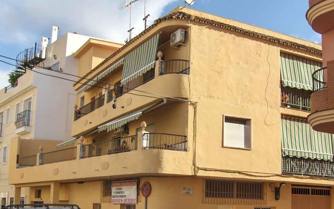 Prédio residencial com toldos de lona listrada verde e branca abertos nas sacadas